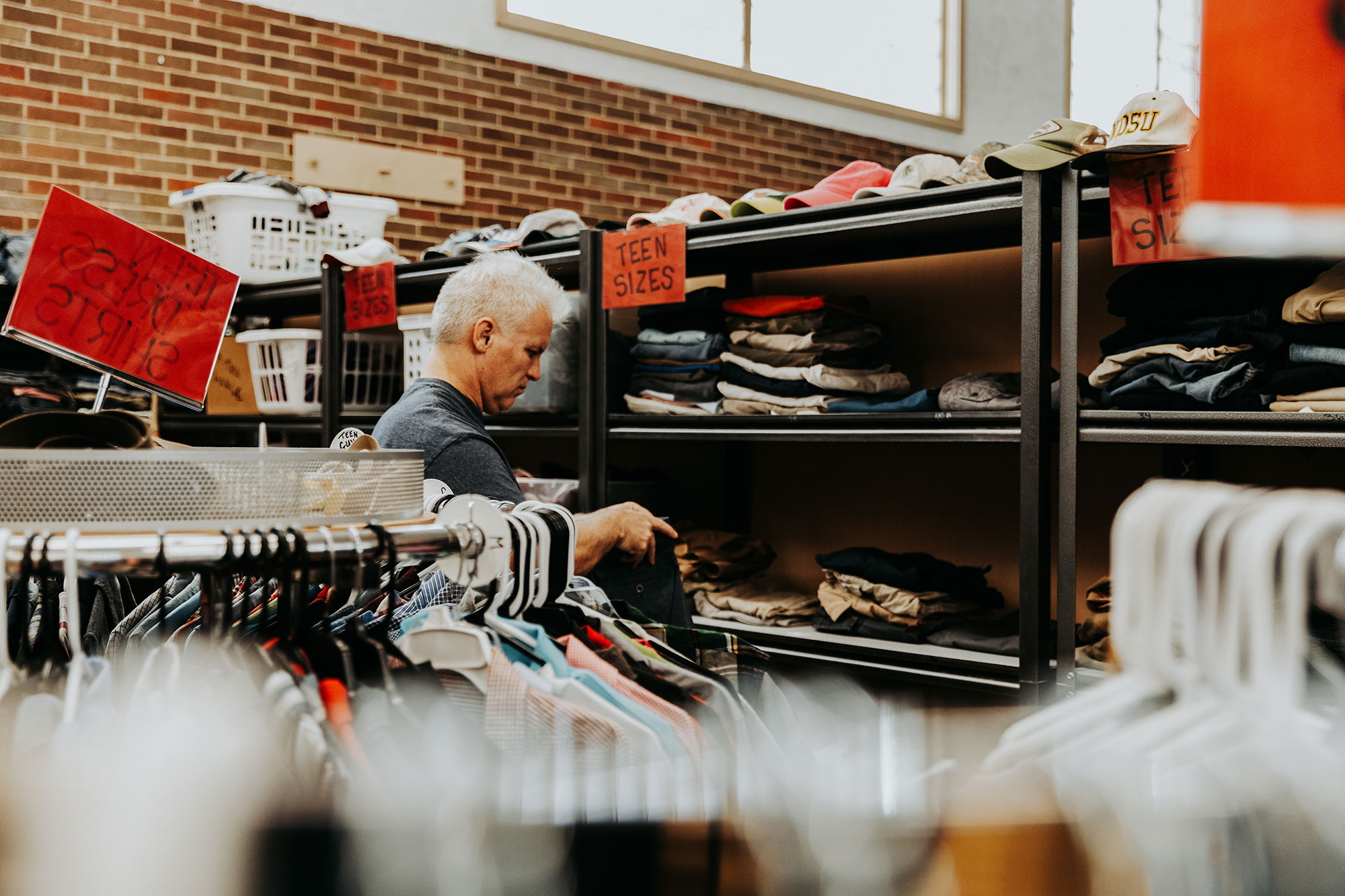 Man stocking shelves with clothing at a charity